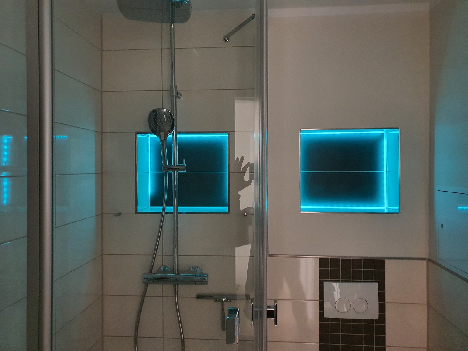 Modernisierte Dusche mit großformatigen Fliesen und Beleuchtung